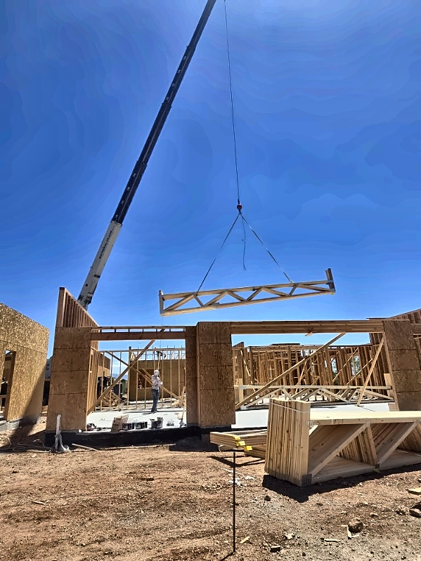Easy Lift crane setting a roof truss over a framed building